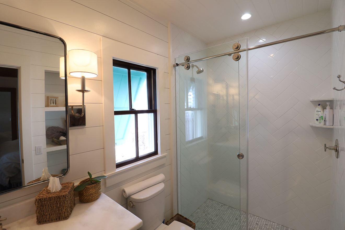 Bathroom vanity with double wall sconces, shiplap walls, and mirror