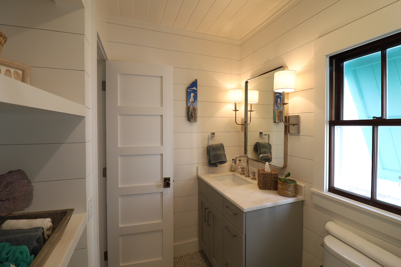 Bathroom with open shelving, double sconces, shiplap ceiling, and tiled floor