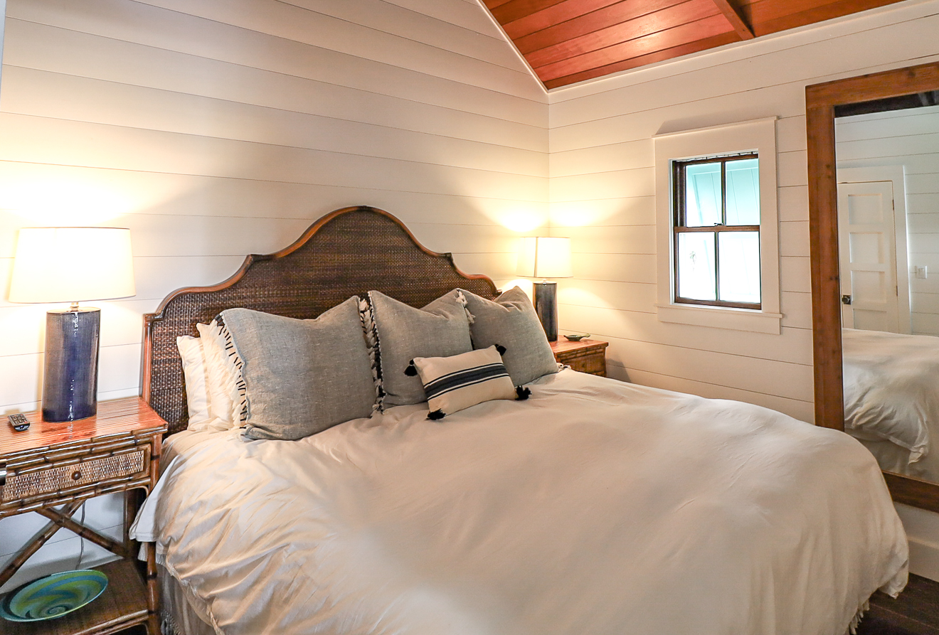 Cottage One king bedroom with red cedar ceiling, shiplap walls, and coastal décor