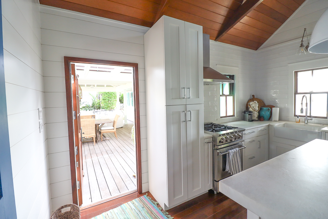 Kitchen showing farmhouse sink, gas range, and view through to covered veranda