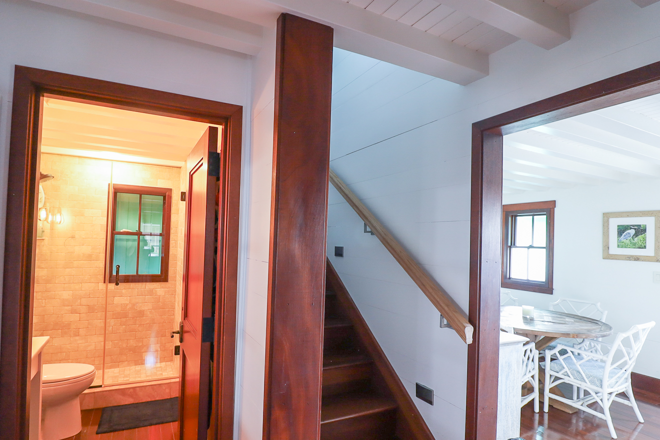 Cottage One interior hallway showing staircase, bathroom door, and dining room beyond