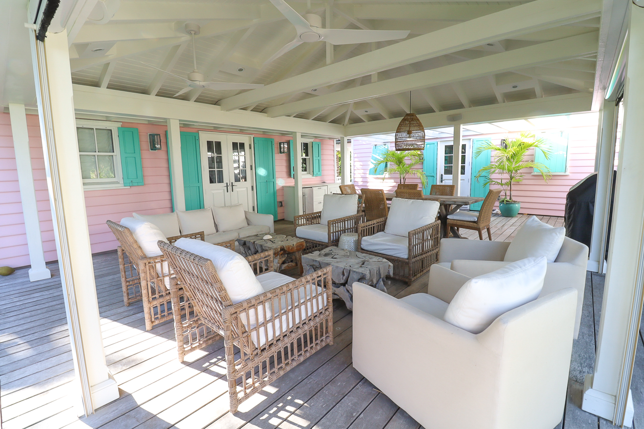Veranda lounge with white sofas and rattan armchairs, cottages beyond