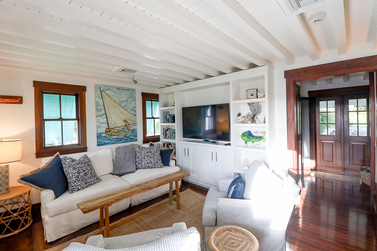 Cottage One sitting room with white sofas, sailboat artwork, and French doors
