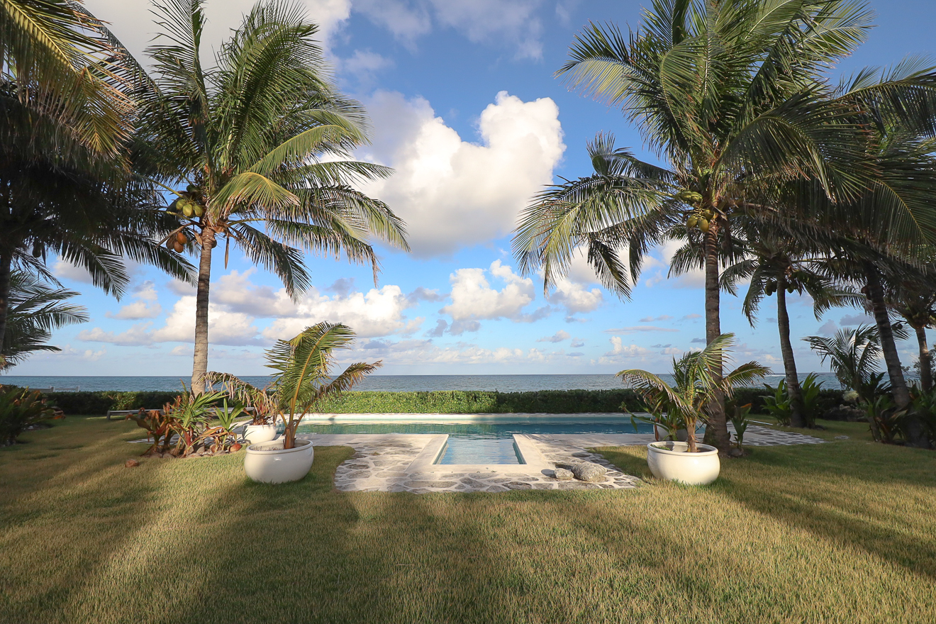 Private pool framed by coconut palms with the Sea of Abaco beyond
