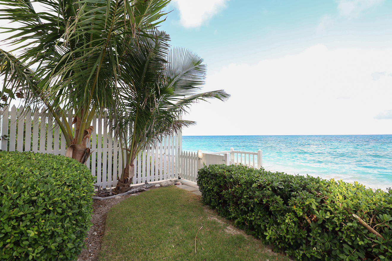 White picket fence, manicured lawn, and the sparkling turquoise ocean
