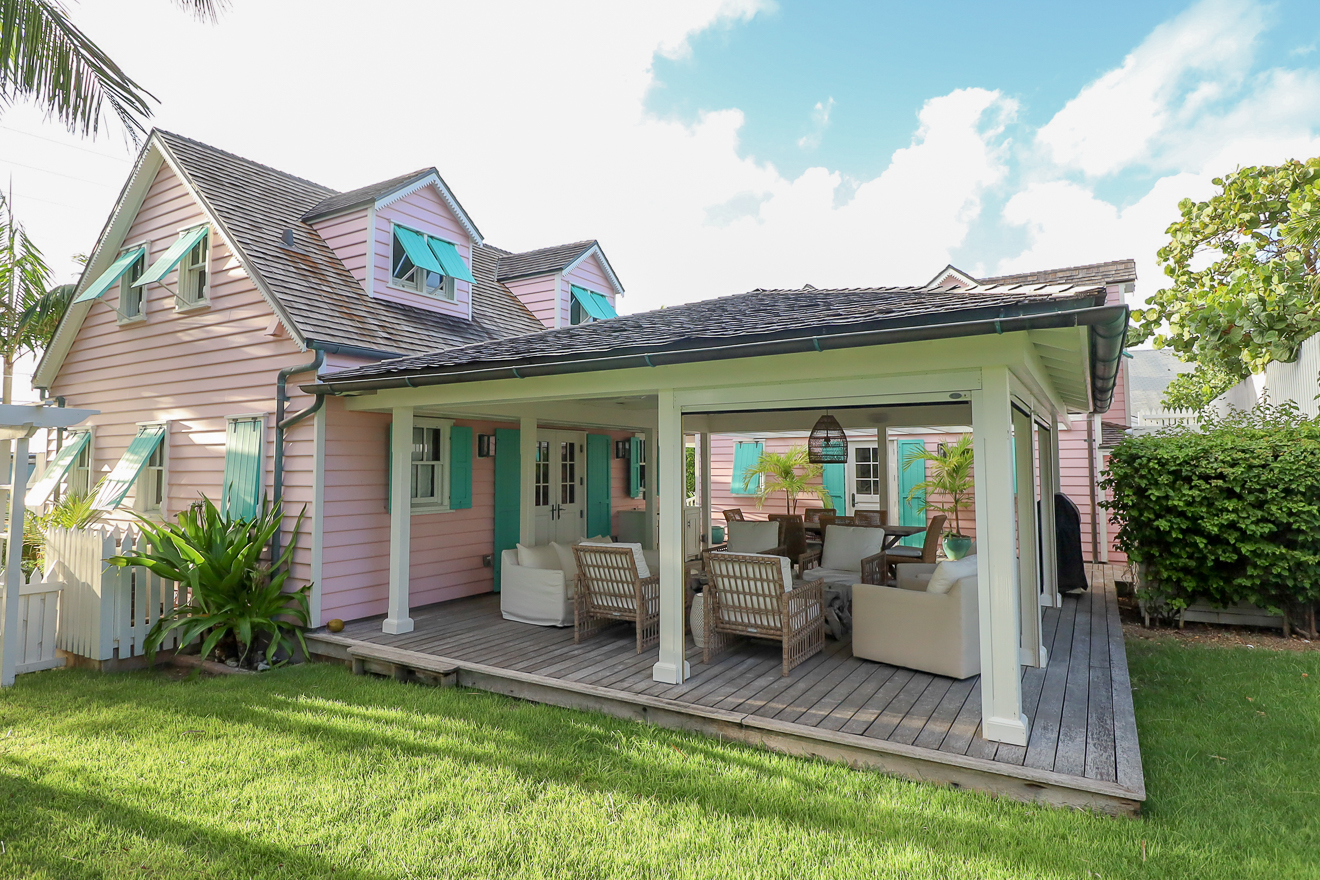 Cottage exterior with covered outdoor living area and manicured lawn